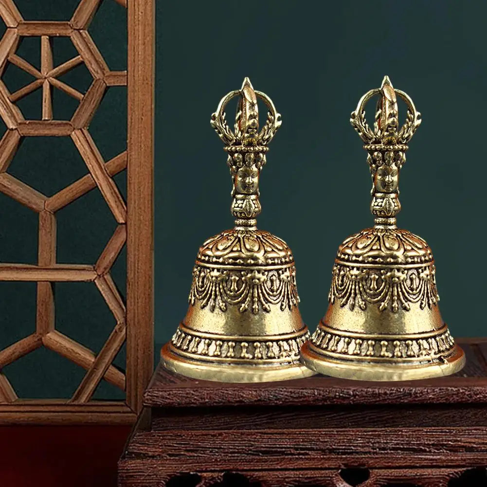 Two ornate golden brass tibetan bells with intricate engravings and crown-like finials in a pestle set buddhist sound healing instruments