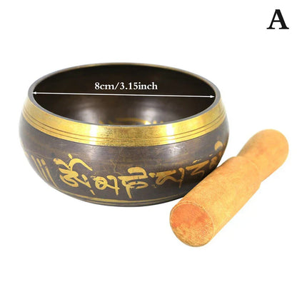 Dark bronze metal singing bowl with gold trim and engraved Sanskrit script for bell yoga meditation with wooden mallet