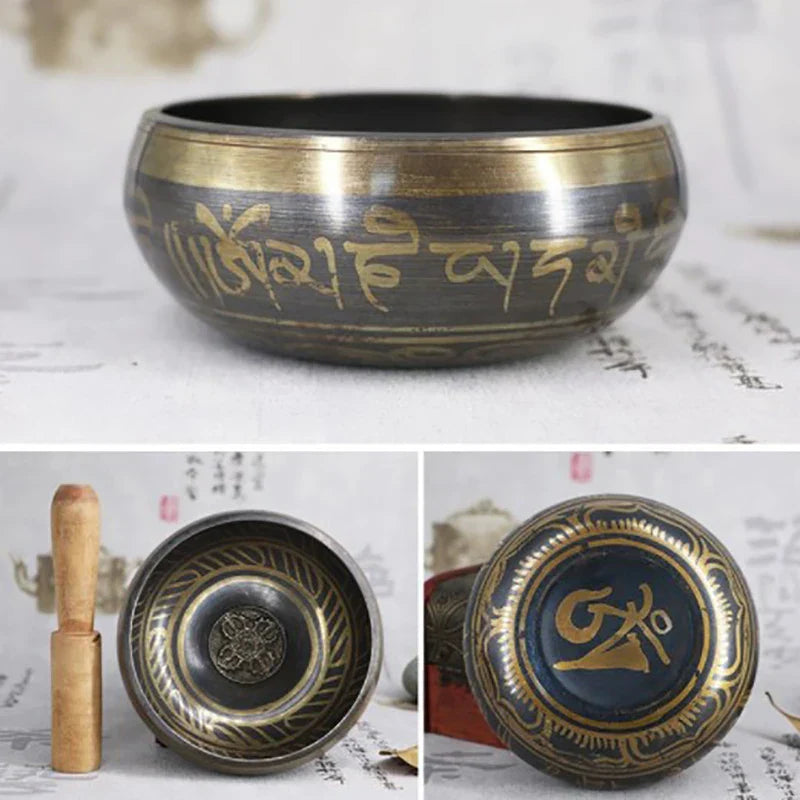 A dark bronze metal singing bowl with gold sanskrit inscriptions and wooden mallet for bell yoga meditation use