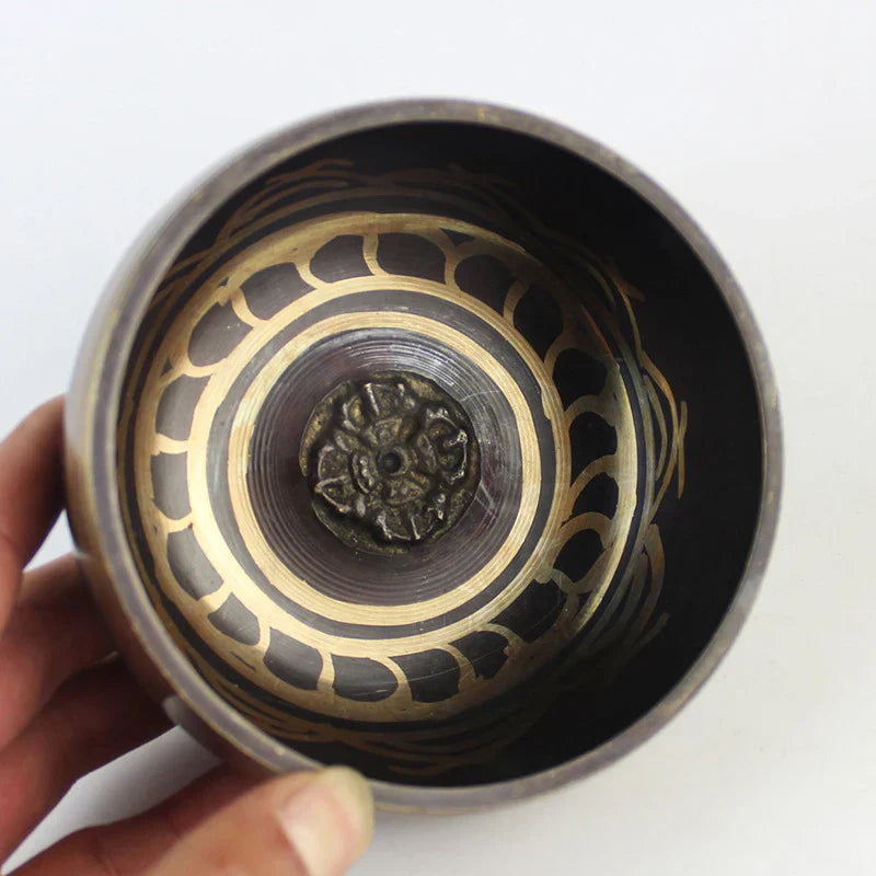 A dark bronze metal singing bowl with gold inlay and floral design for bell yoga meditation and buddha sound bowl use