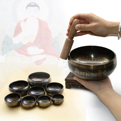 Hand holding a dark bronze metal singing bowl with engraved Tibetan script for bell yoga meditation and chanting