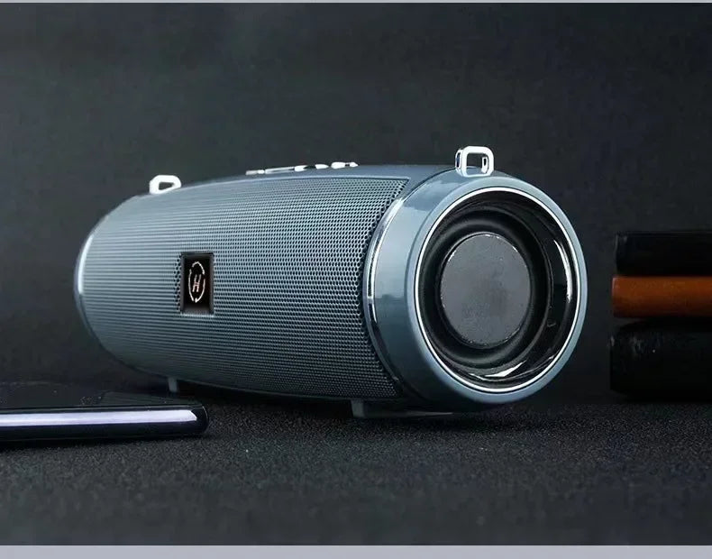 Gray cylindrical portable wireless speaker with textured mesh grille and chrome accents for high power outdoor stereo surround TWS use