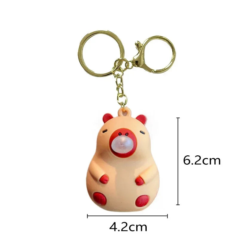 Cute beige and red capybara doll pinch keychain with glowing spit bubble decompression attached to gold schoolbag doll pendant rings