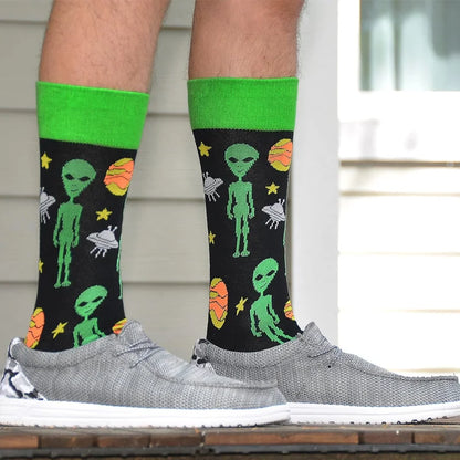Green knitted cavertin men’s programming alien sasquatch socks with orange planets on black background for sasquatch dad music fans