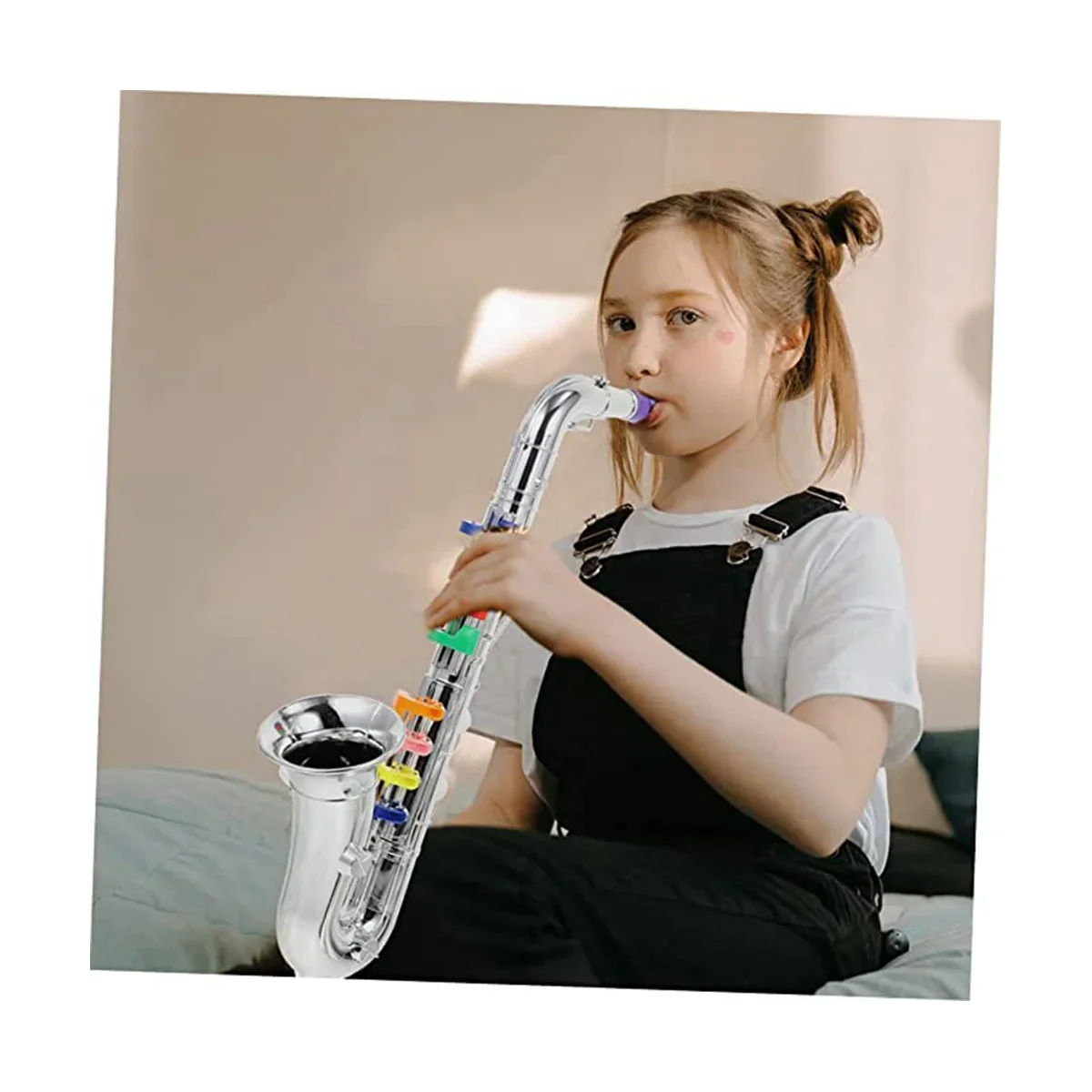 A child holds a shiny silver brass toy saxophone with colorful plastic keys from children’s saxophone music toys