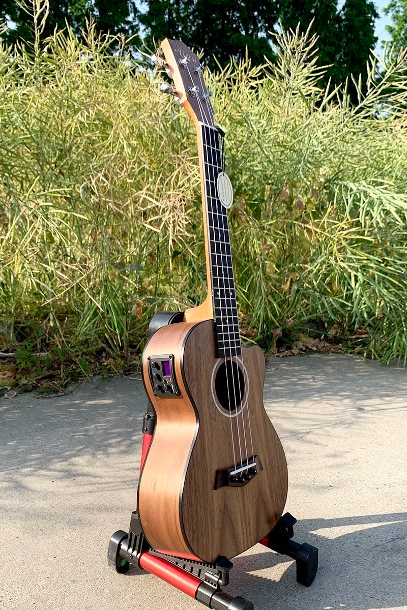 A light brown wooden aiersi brand concert ukulele custom with black fretboard and built-in pickup on red stand