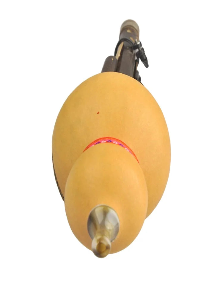 A golden-yellow chinese handmade hulusi with a metallic mouthpiece and red band in cucurbit c tune for beginner music lovers