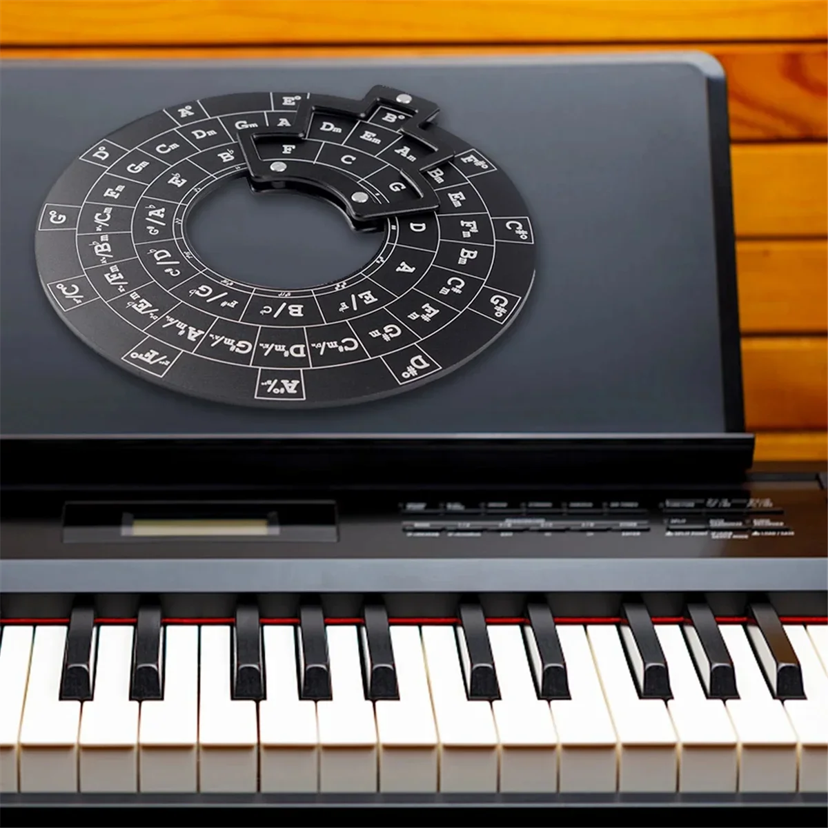 Black circular wooden chord wheel with white lettering and central cutout on electronic keyboard for music theory