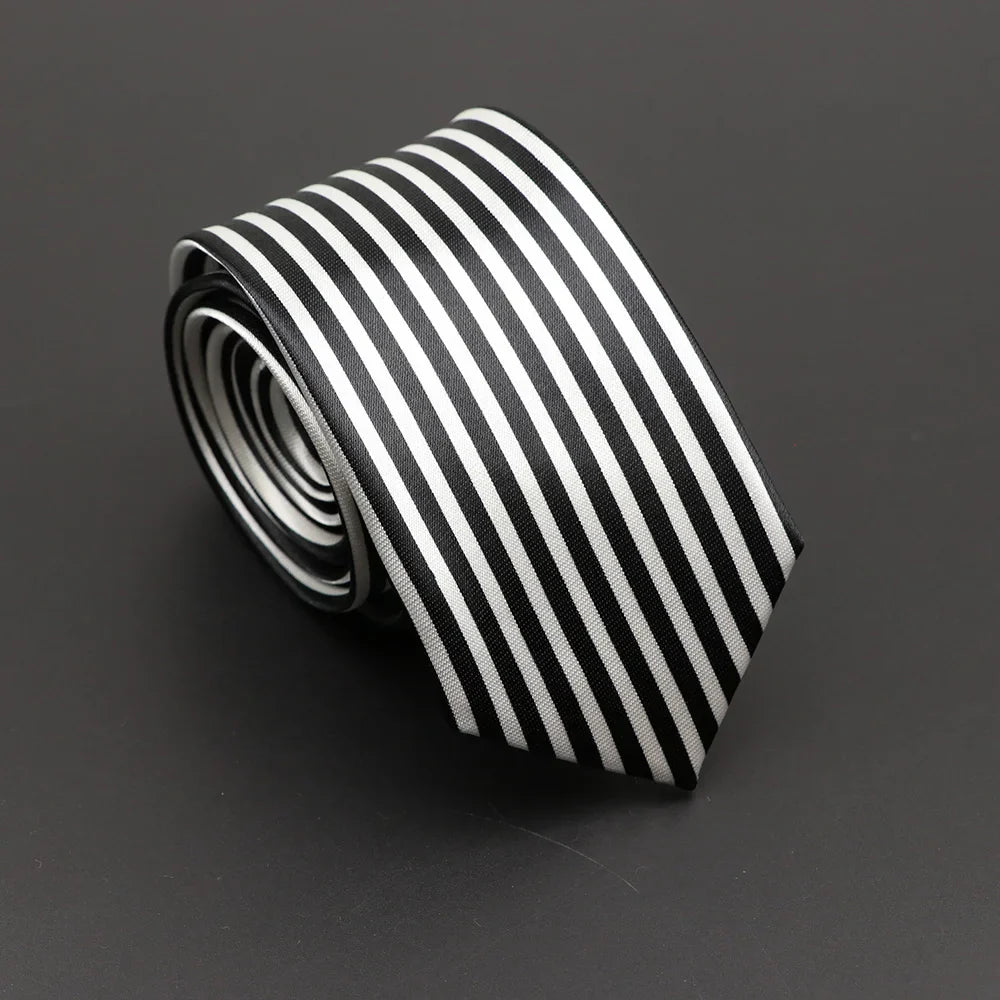 A sleek black and white silky narrow necktie with classic musical notes printed design and a pointed tip coiled neatly