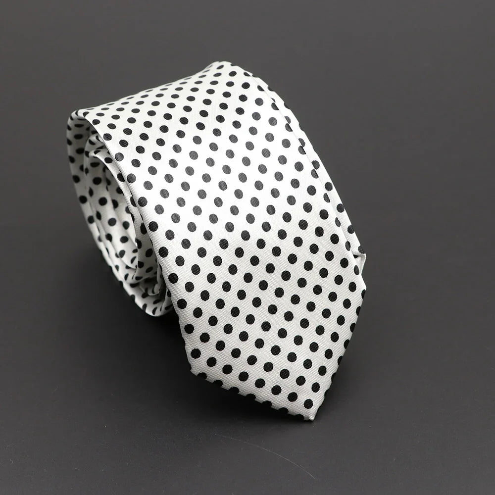 A silky narrow necktie in white with evenly spaced black polka dots resembling a classic musical notes design