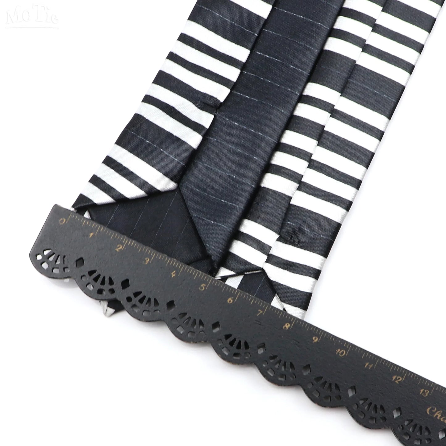 Black and white silky narrow neckties with classic musical notes and subtle pinstripe pattern displayed with black ruler