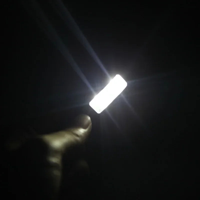 A bright white rectangular led clip-on music stand light with dual arms held in hand for piano violin musical use