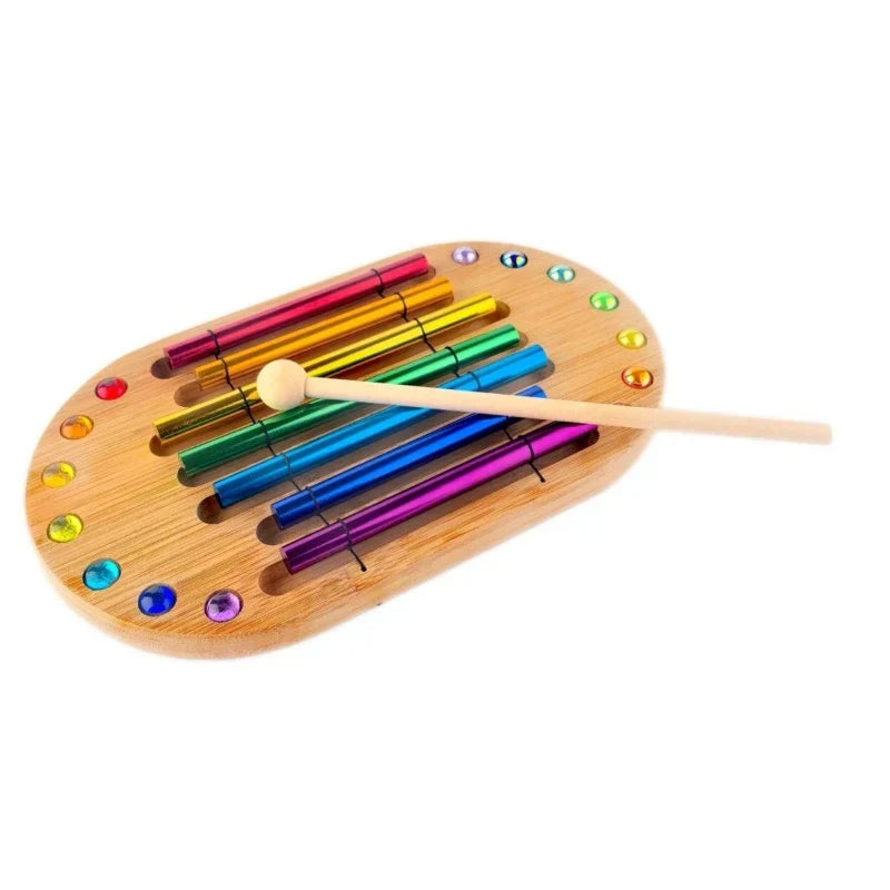 Rainbow-colored metallic tubes on wooden base with gemstones and mallet for colorful sound bundle meditation spiritual healing energy percussion instruments