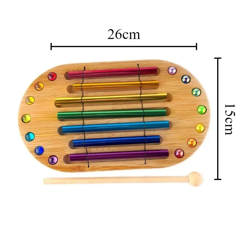Rainbow-colored metallic tuning forks in a wooden frame with gemstones and mallet for colorful sound bundle meditation spiritual healing