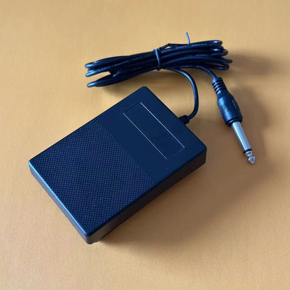 Black plastic compact sustain pedal with textured surface and coiled cable for keyboards drum machines and synthesizers
