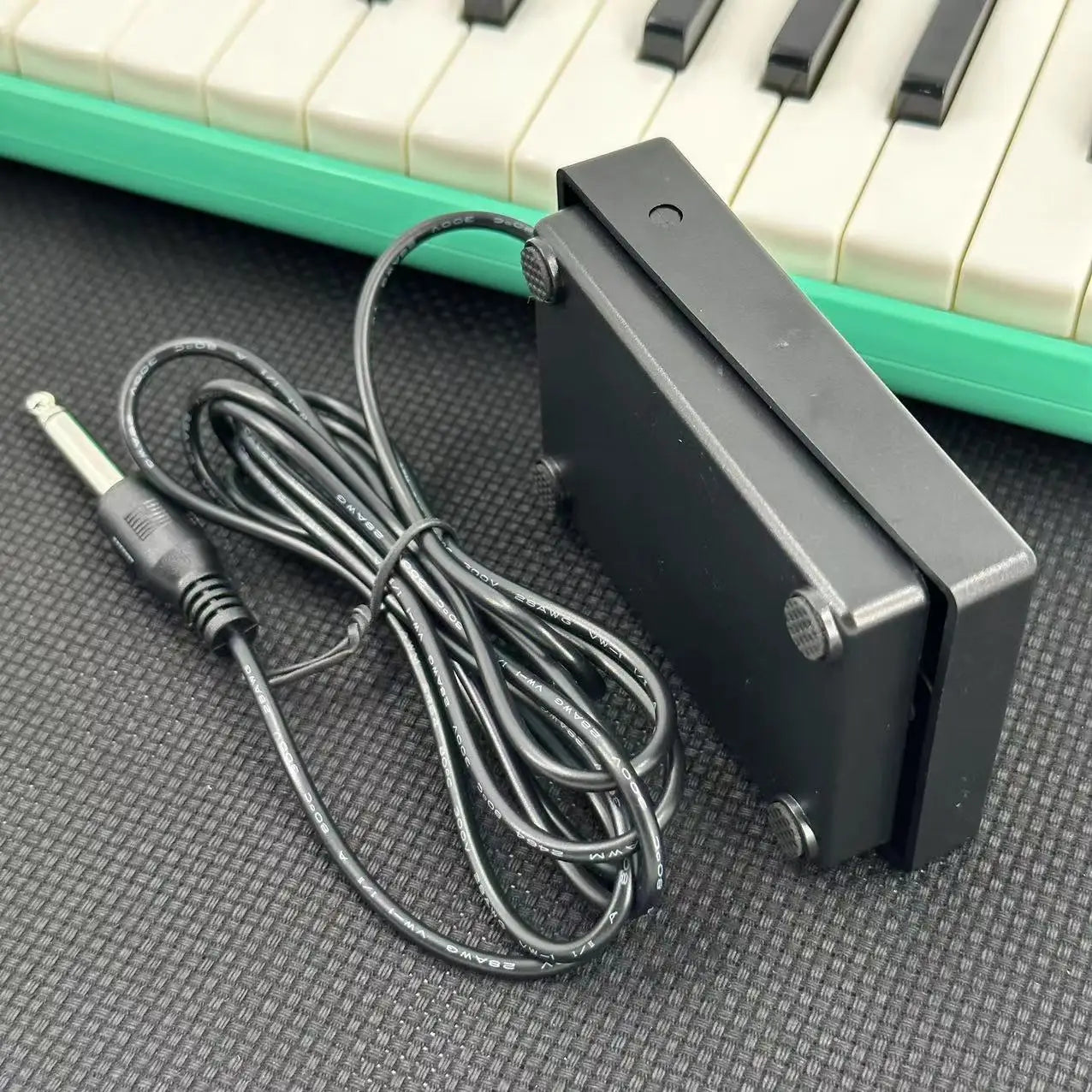 Black compact sustain pedal with coiled cable and 1/4 inch plug for keyboards drum machines and digital pianos