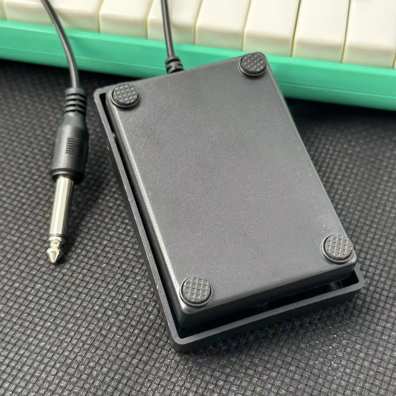 Compact sustain pedal with black plastic body textured rubber feet and 1/4 inch plug for keyboards drum machines and synthesizers