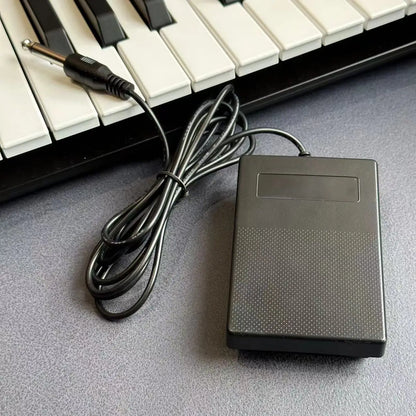 Black plastic compact sustain pedal with textured surface and coiled cable for keyboards and drum machines