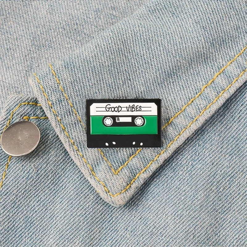 A black and green creative music symbol enamel pin with good vibes text and glossy finish in headset alloy brooch style