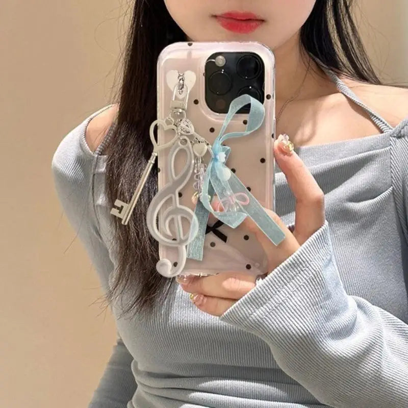 Transparent phone case with black polka dots featuring a decorative note keychain bowknot and light blue handbag backpack pendant