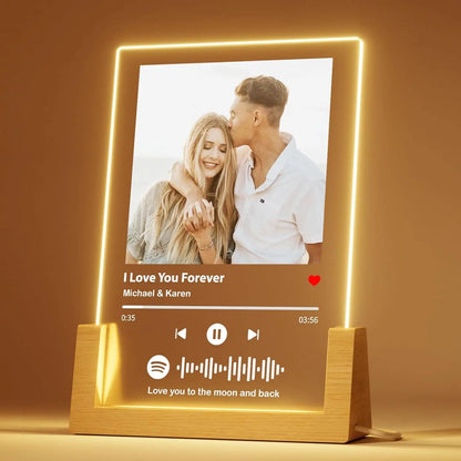 Golden led-lit personalized music plaque with wooden base and glowing border displaying couple photo and song details