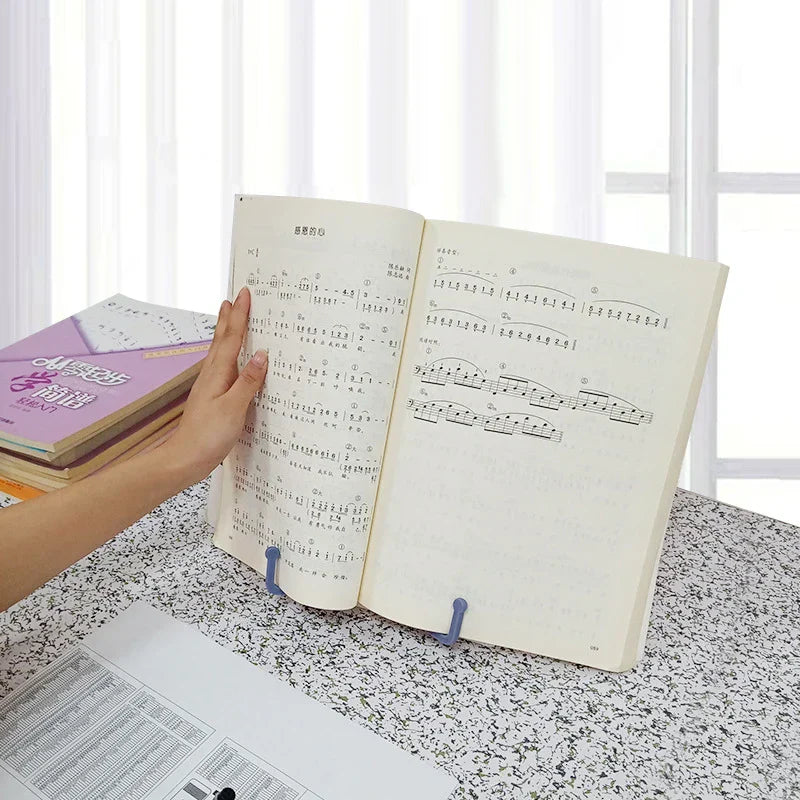 Blue plastic foldable desktop sheet music stand holding open music sheet ideal for children reading and guitar use