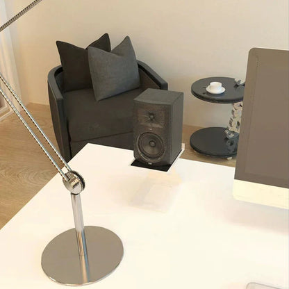 Black rectangular studio monitor speaker with woofer and tweeter grille on a speaker stand professional for bookshelf speakers