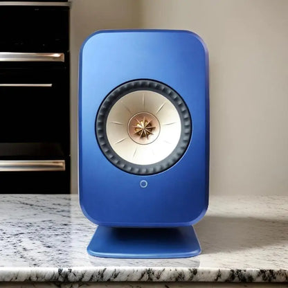 Blue kef ls50 wireless speaker with cream cone and gold center on professional studio monitors speaker stands