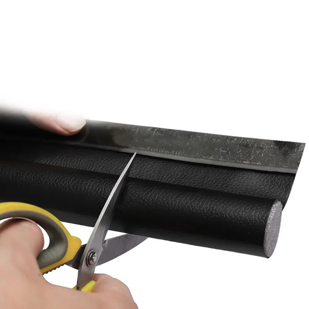 Black faux leather roll with textured surface being cut by yellow scissors for adjustable sound-proof door strip gap blocker