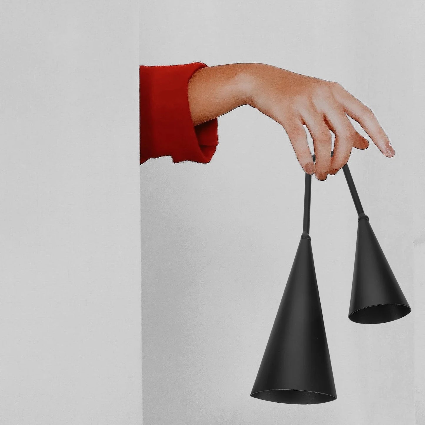 Black metal double trumpet agogo bells with slender handles held by a hand in red sleeve este cencerro percussion instrument