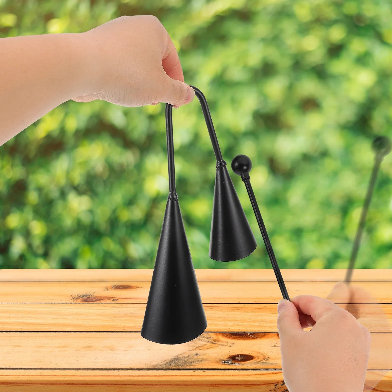 Black metal double trumpet agogo bells with curved handle and matching mallet as este cencerro percussion instrument