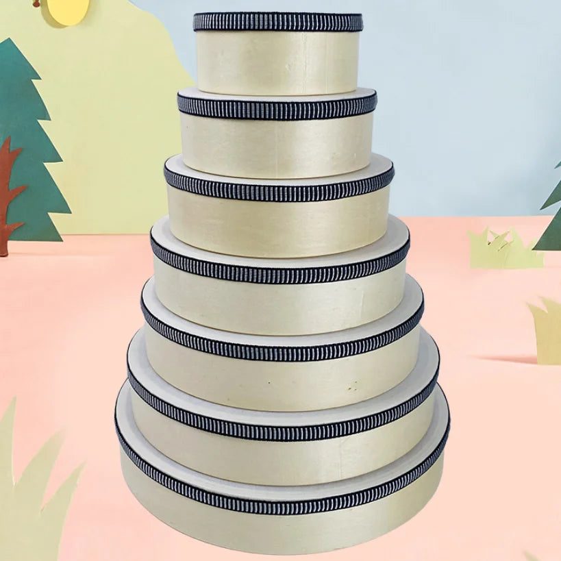Stack of cream-colored round educational wooden hand beat percussion harp drum music instrument toy boxes with black ribbon trim