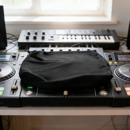 Black elastic dust cover fabric pouch resting on dj mixer as a protective mixer dustproof cover for studio sound equipment