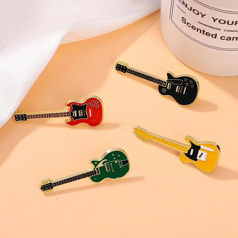Four colorful enamel electric guitar brooches with metallic gold outline and black fretboard details for personalized use