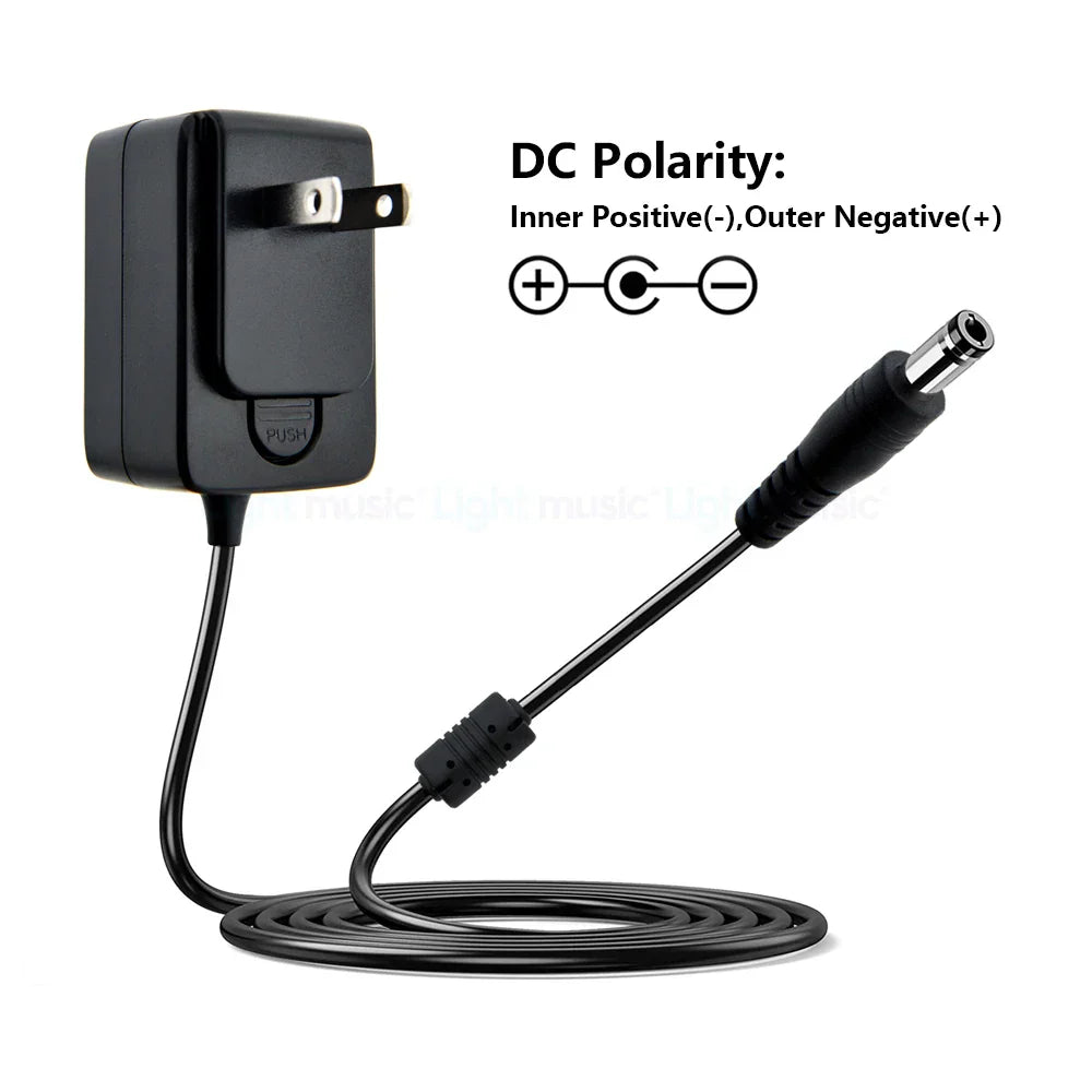 Black plastic electric guitar pedal power adapter with coiled cord and dc plug featuring stoving varnish finish