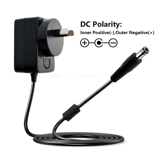 Black plastic electric guitar pedal power adapter with uk plug and coiled cable featuring true bypass design