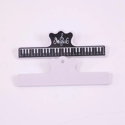Electronic piano music stand with black and white piano-key clip and crown-shaped music logo for sheet music display