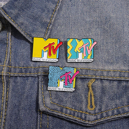 Three colorful enamel music television pins with vibrant yellow and pink logos as brooches lapel backpack badges
