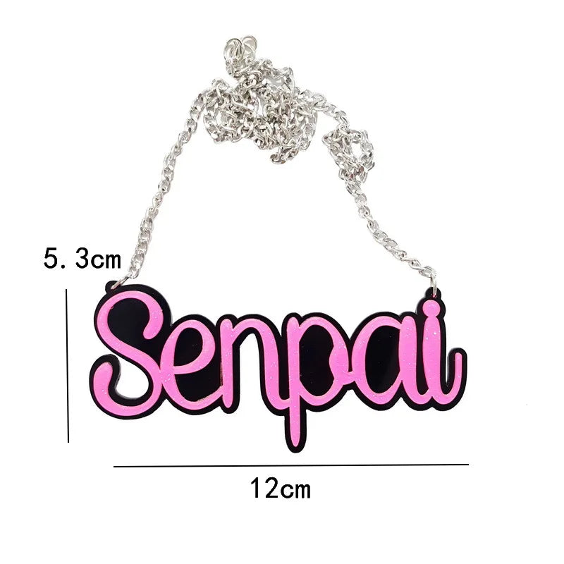 A pink and black senpai acrylic necklace with a silver chain featuring black letter halloween design for necklace street trend