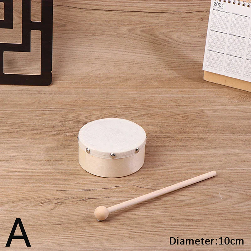 A small cream-colored wooden frame drum with a white head and silver rivets with a drum stick set for kids educational toy