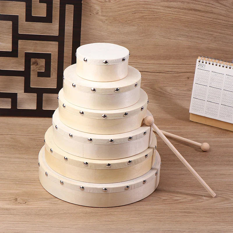 Stacked set of five cream-colored wooden frame drums with silver metal studs and matching drum stick set for kids educational toy