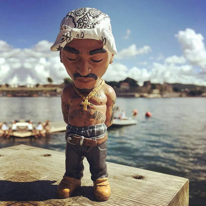 A detailed resin statue of tupac shakur bobblehead wearing a white bandana and denim pants for home decor hop rapper funny
