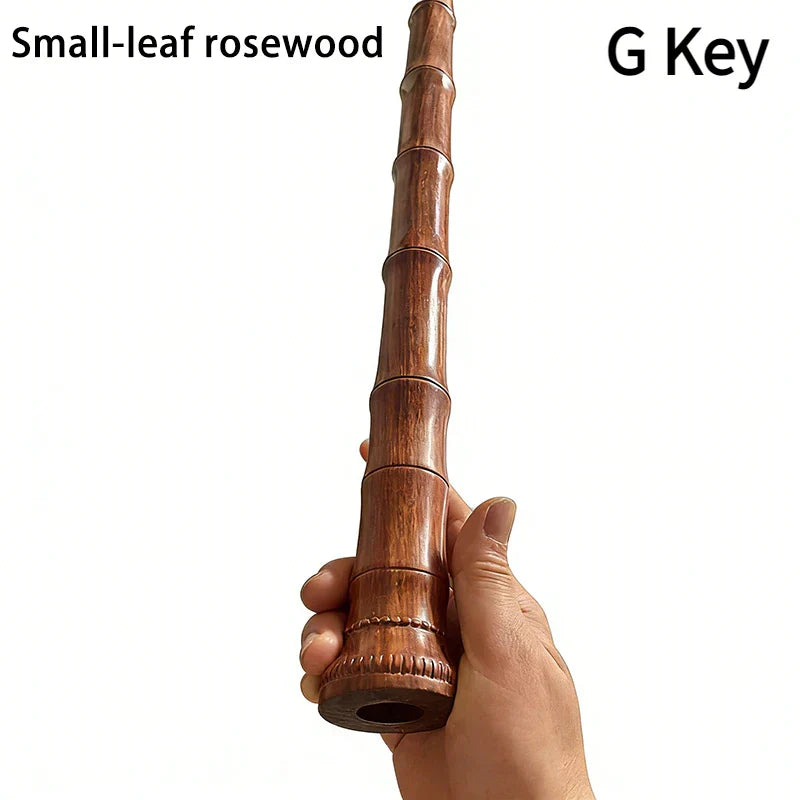 A hand holds a slender polished small-leaf rosewood g key for a key wooden xiao handmade diy chinese vertical bamboo flute