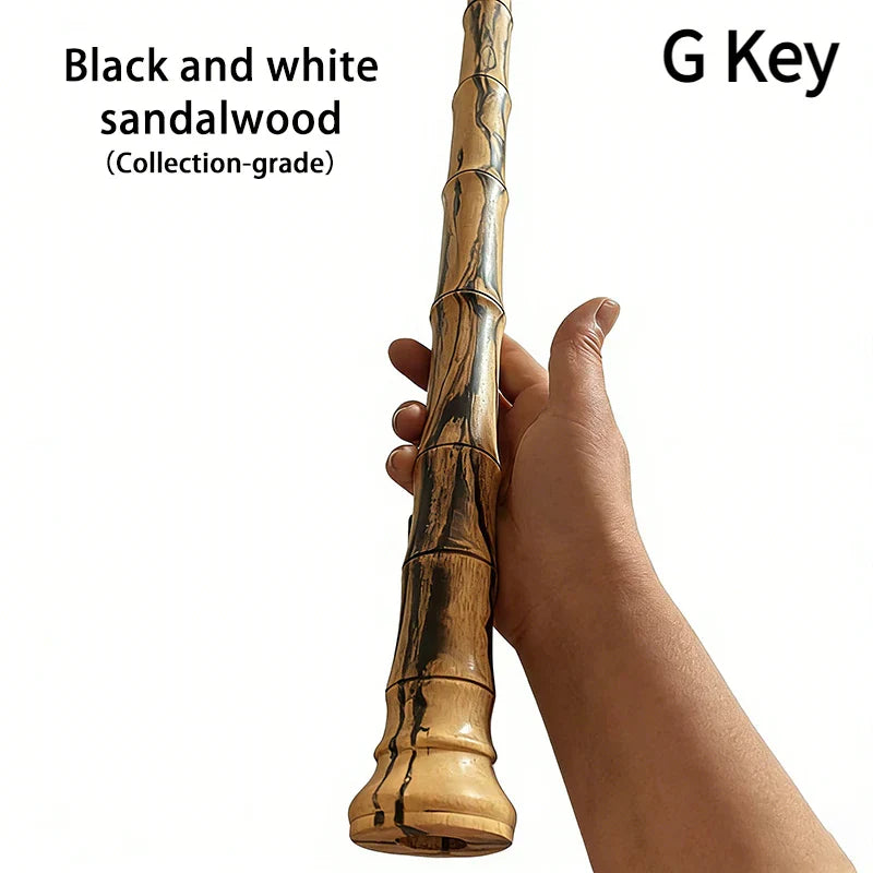 A hand holds a collection-grade black and white sandalwood key wooden xiao keychain with bamboo-like segmented design
