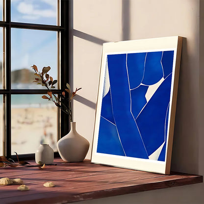 A framed modern graphic poster featuring bold blue geometric shapes on white in a light wood frame for wall art