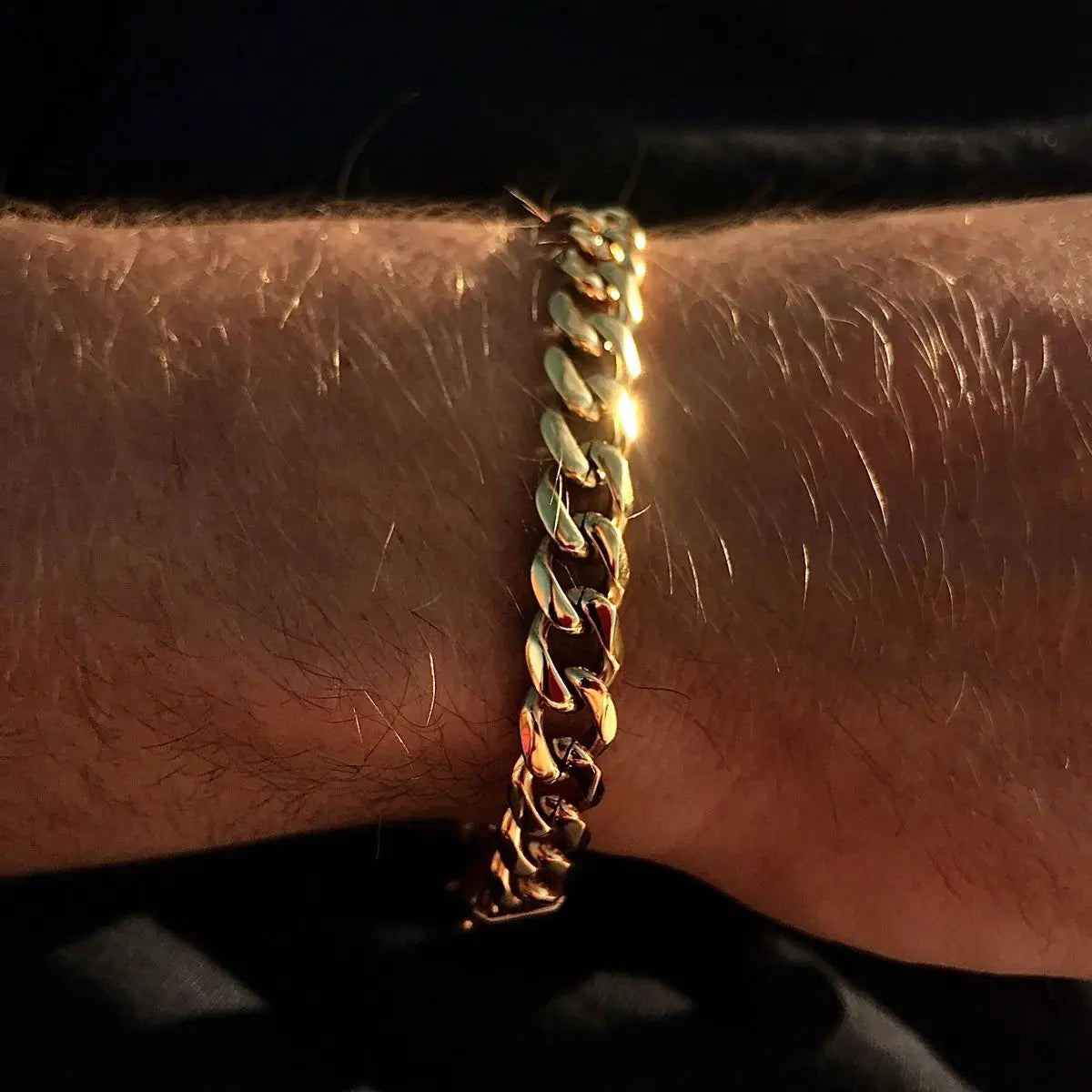 A gold color cuban chain bracelet made of stainless steel worn on a hairy wrist for hip hop male style