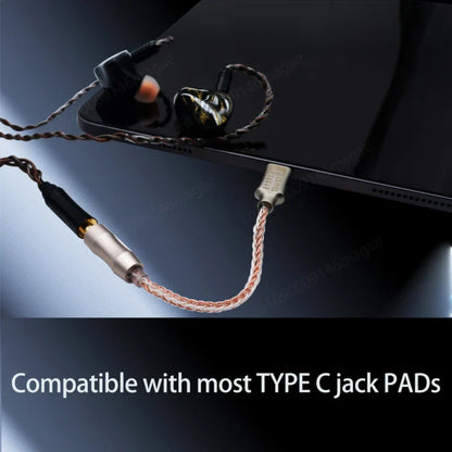 Black and gold inlaid earphones with braided copper cable connected to graveaudio da06 cx31993 audio decoder iem amp mobile