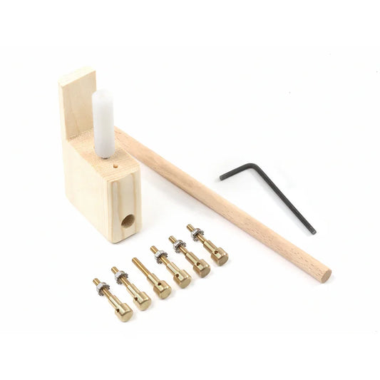 Light-colored wooden guitar bridge doctor with brass fittings and black l-shaped wrench for musical instrument manufacturing