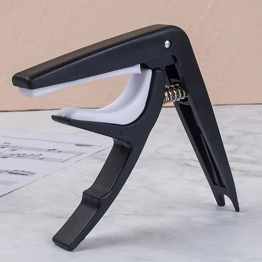Black plastic guitar capo with white rubber grip and metal spring for acoustic classic guitar and musical instrument ukulele use