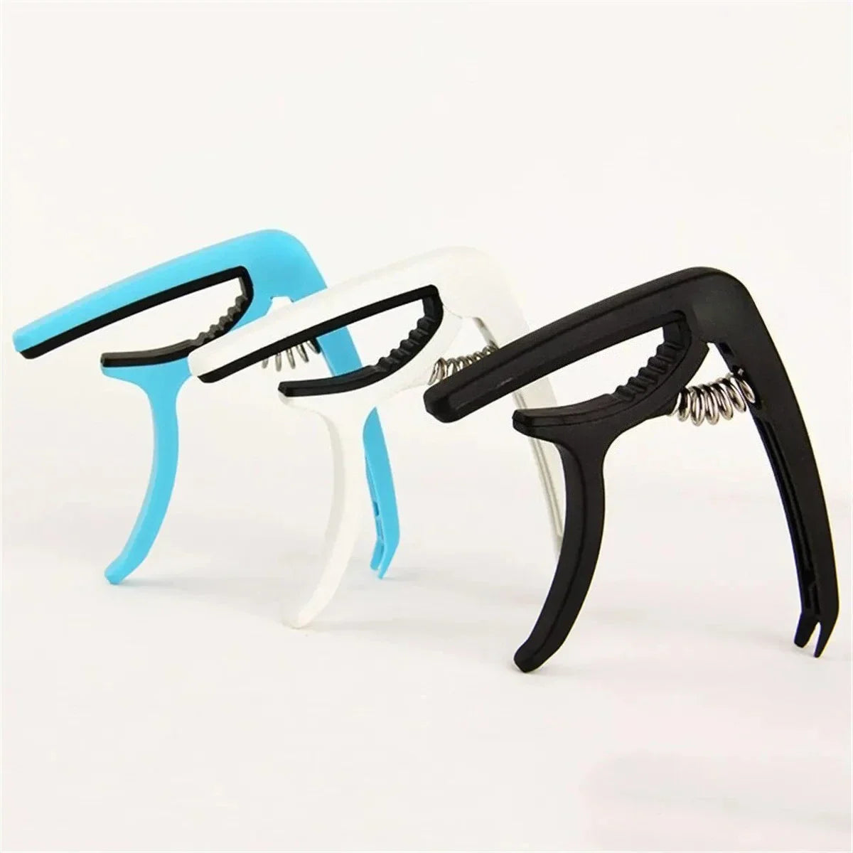 Three spring-loaded guitar capos in blue white and black for acoustic classic guitar and musical instrument ukulele tuning clamp